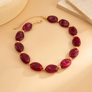 Dettaglio di perle in resina marmorizzata rossa con accenti dorati e chiusura
