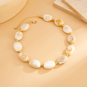 Dettaglio della collana con perle ovali in resina marmorizzata e sfere dorate su pietra