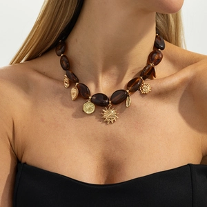 Dettaglio della collana di resina ambrata con ciondoli a forma di sole oro