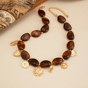 Collana boho con perline in resina ambra e ciondoli dorati su uno sfondo beige chiaro