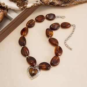 Dettaglio macro della collana di perle in resina ambrata con pendente a cuore in argento