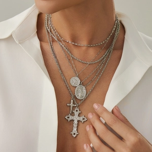 Dettaglio di collane a più strati argentate con pendenti a croce e medaglie religiose
