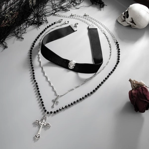 Three-piece gothic necklace set with cross pendants and skull choker on a dark background