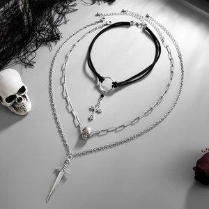 Detail of gothic multi-layer necklace set with silver cross, skull, and dagger pendants
