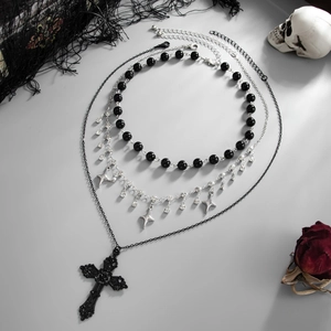 Macro shot of gothic layered necklace with cross pendant and skull prop decor