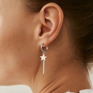 Close-up of silver star and long bar dangle earring worn on a female ear lobe