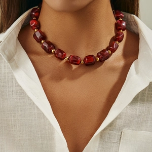 Collana etnica con perle di resina bordeaux e distanziali dorati su lino bianco