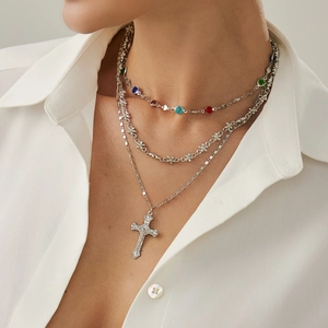 Dettaglio della collana argentata a strati con strass colorati e ciondolo a croce