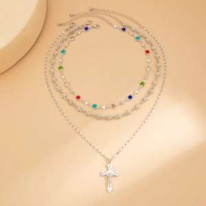 Dettaglio collana argentata a tre strati con strass colorati e ciondolo a crocifisso