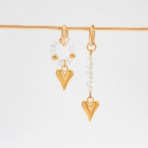 Detail of asymmetrical gold earrings with clear faceted beads and heart-shaped charms