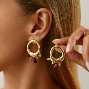 Detailansicht goldener Hammerschlag-Ohrringe mit bunten Perlenquasten im Retro-Stil