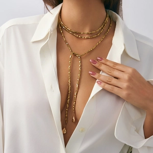 Detail van gouden Y-ketting met kubuskralen en druppelvormige hangers voor dames