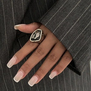 Anello in argento irregolare con pietra acrilica grigia su sfondo gessato elegante