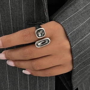 Anello aperto moderno con cristalli acrilici grigio scuro indossato su un abito gessato