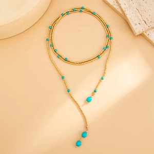 Macro-opname van gouden kralenketting met turquoise stenen en elegante lange kwastjes