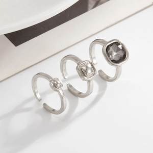 Détail de bagues carrées argentées serties de cristal gris sur fond blanc pur