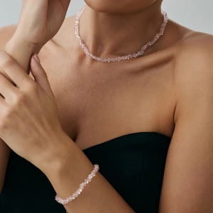 Dettaglio di un set con collana e bracciale in cristallo rosa indossato da una modella