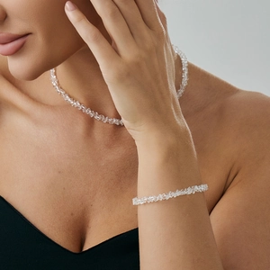 Dettaglio macro del set collana e bracciale in cristallo trasparente su collo e polso