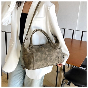 Dettaglio di una borsa Boston vintage in pelle con doppi manici e tasche laterali