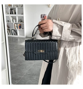 Detail der schwarzen geflochtenen Ledertasche mit goldenem Drehverschluss und feiner Textur