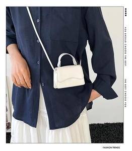 Dettaglio della mini borsa bianca in ecopelle con patta a onda e tracolla sottile