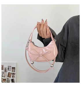 Dettaglio della borsa a mezzaluna in vernice rosa con fiocco decorativo e sfere in metallo