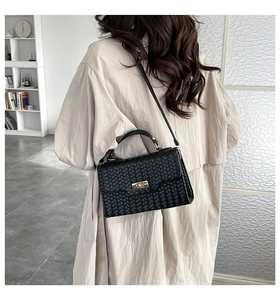 Detailed back view of a black woven leather crossbody bag worn with a beige shirt