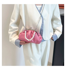 Detail of pink pleated cloud bag with oversized pearl handle and silver chain strap