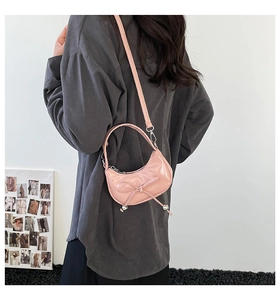 Borsa a mezzaluna rosa in vernice con fiocco indossata a tracolla dalla modella