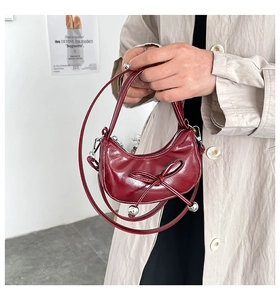 Dettaglio borsa lucida rosso vino con fiocco elegante e ciondoli a sfera in metallo argento
