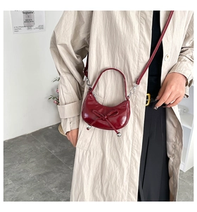 Dettaglio della borsa a mezzaluna bordeaux con fiocco decorativo e sfere argento