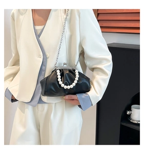 Detail of black pleated cloud bag with white pearl handle and silver chain strap