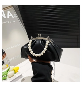 Detail of black pleated cloud bag featuring silver clasp and white pearl handle