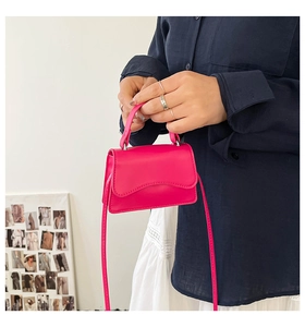 Dettaglio di una mini borsa fucsia con trama liscia e tracolla regolabile