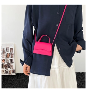 Dettaglio mini borsa a tracolla rosso rosa con bordo ondulato e tracolla sottile