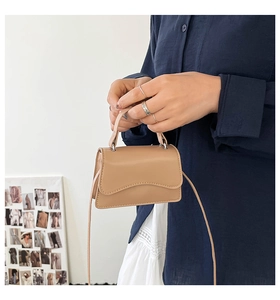 Dettaglio mini borsa beige con bordi a conchiglia e fibbie in argento lucido