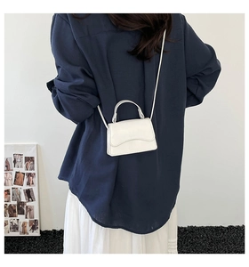 Dettaglio mini borsa bianca a tracolla in pelle sintetica indossata da una modella