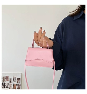 Mini borsa rosa con patta ondulata tenuta da una modella in un ambiente interno casual
