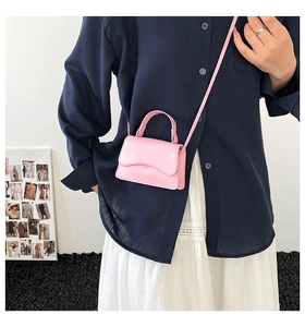 Dettaglio della mini borsa a tracolla rosa con patta a onde e sottile tracolla abbinata