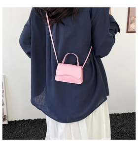 Mini borsa a tracolla rosa con patta ondulata indossata da una modella in città