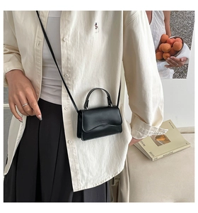 Dettaglio della mini borsa in pelle nera con eleganti cuciture curve e tracolla sottile