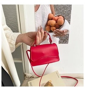 Dettaglio della borsa rossa con patta a conchiglia tenuta da una modella in stile minimal