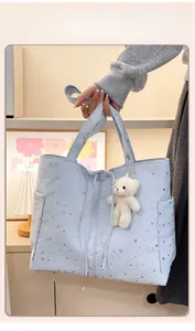 Dettaglio della borsa tote in tessuto azzurro con stelle argentate e ciondolo a orsetto