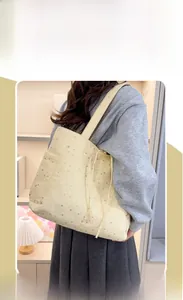 Dettaglio della borsa tote beige con stampa a stelle indossata a spalla dal modello