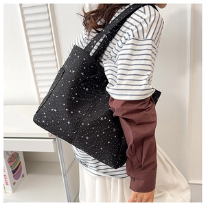 Borsa tote in tela nera con motivo a stelle bianche indossata per mostrare la taglia