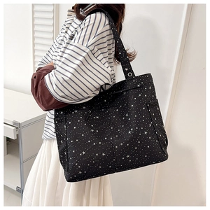 Vista laterale di una borsa tote nera con stampa a stelle e pratiche tasche laterali