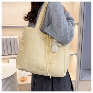 Vista dettagliata della borsa tote gialla in tela con stelle argentate e ciondolo peluche