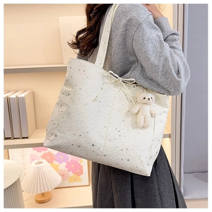 Dettaglio della borsa tote in nylon bianco con stelle argento e ciondolo orsetto