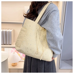 Dettaglio della borsa tote in tela beige con stampa di stelle argentate e tasca laterale