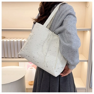 Dettaglio della borsa tote bianca con stelle argentate e coulisse decorative laterali